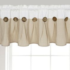 a curtain with buttons hanging from it's side in front of a white window