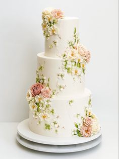 a three tiered wedding cake with flowers on the top and bottom, sitting on a plate