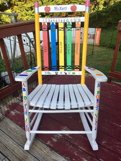 a white wooden chair with colorful markers on it's back and sides sitting on a deck