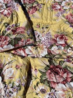 a yellow floral bed spread with pink and white flowers on it's side,