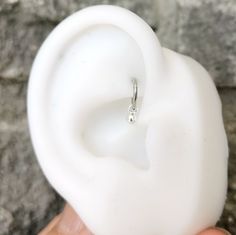 a close up of a person's hand holding a fake ear with a ring on it