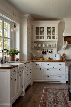 a kitchen filled with lots of white cabinets and counter top space next to a window