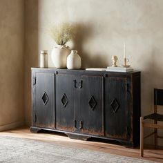 a black cabinet with two vases on top of it