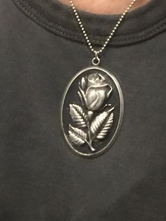 "this is a vintage sterling silver pendant with a rose made by International Silver Company (stamped on back).  The oval shape measures approximately  2 3/8\" long X 1 1/2\" across the center, so it's fairly large.  (see photo on neck) There is a loop  and a jump ring at the top where it can be attached to a chain which is not included. The pendant is hollow and the front has a raised, slightly open rosebud on a short stem with three beautiful leaves. The rose is silver and stands out from the black patina of the background. Like the rose itself, the edge of the pendent is a thin shiny silver border. The back side is flat, polished silver, and hallmarked.  This piece was worn by my mother, so please note that some tiny but not very noticeable areas of the patina have come off, so a bit of Cheap Metal Necklace With Flower Pendant, Rose Shaped Urn Necklace Sterling Silver, Beautiful Leaves, Wear Necklaces, Rose Necklace, Polish Silver, Love Rose, Wooden Jewelry, Shiny Silver