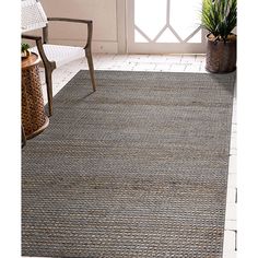 the rug is on the floor next to a chair and potted plant in front of an open door