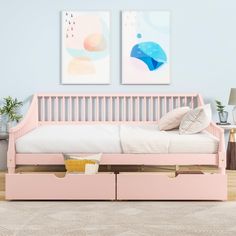 a pink day bed with two pictures above it