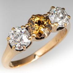 This antique circa 1881 ring is accented with one (1) old European cut fancy colored diamond and two (2) old European cut near-colorless diamonds set into six- prong settings. The ring measures 6.5mm at the top, rises 4.5mm above the finger, tapering to 1.9mm wide and 1.1mm thick at the base of the shank. It is currently a size 5.75 and it has a date of 1881 hand engraved inside the shank. The center diamond is lightly chipped but this cannot be seen without jewelers magnification. Antique Engagement Rings Sapphire, Estate Jewelry Rings, Wedding Ring Diamond Band, Colorless Diamond, 18k Yellow Gold Ring, Antique Engagement Rings, European Cut Diamonds, Fancy Color Diamonds, Sapphire Engagement