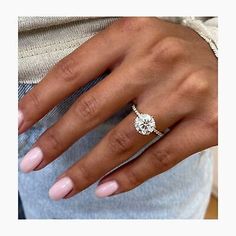 a woman's hand with a diamond ring on her finger and pink manicured nails