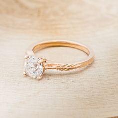 a close up of a ring on a wooden surface with a diamond in the center