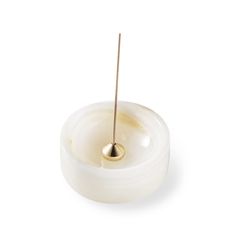 a candle with a stick sticking out of it's center on a white surface