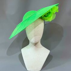 Cool lime green sinamay straw cloth saucer with a peekaboo silk flower underbrim, and accented with graceful curls of sinamay.﻿ Universally flattering, this large saucer style suits most any wearer. Headband, elastic, and comb attachment for easy, comfortable wear. Lifted Millinery headwear is constructed with time honored techniques and fine craftsmanship. All hats are meticulously blocked and sewn by hand without the use of adhesives to attach trims. This ensures a long lasting hat with the ability to be retrimmed throughout the years. A hat box for careful storage is included with every hat purchase. Please allow one week, from date of purchase, for your hat to be shipped. Green Fitted Fascinator For Kentucky Derby, Green Fitted Fascinator For Races, Green Fitted Fascinator For Church, Fitted Green Fascinator For Races, Green Fitted Fascinator For Garden Party, Green Adjustable Brimmed Fascinator, Green Fascinator For Garden Party, Elegant Green Fascinator For Church, Adjustable Green Fascinator For Garden Party