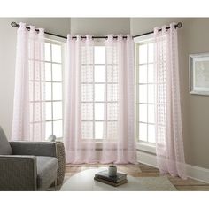 a living room filled with furniture and windows covered in pink sheer curtain panels, along with a white rug