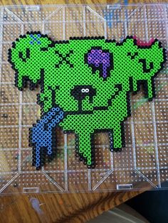 the pixel art is made to look like a green dog with two purple hearts on it's chest