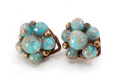 two pieces of jewelry sitting on top of a white surface with gold and blue speckles