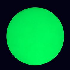 a large green ball is lit up in the dark