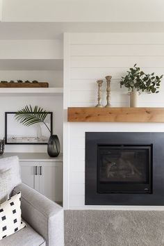 a living room filled with furniture and a fire place in front of a white wall