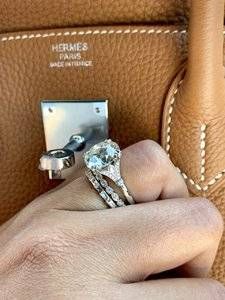 a woman's hand holding onto a brown purse with two rings on the handle