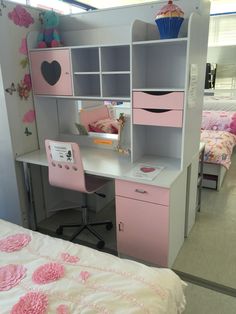 a pink and white desk with drawers, shelves and a cupcake on it