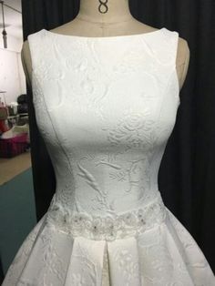 a white dress is displayed on a mannequin