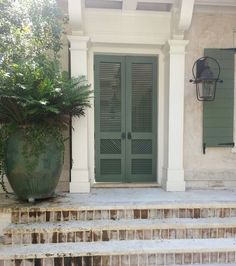 a large green planter sitting on the side of a set of steps next to a door