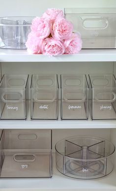 clear storage bins with labels on them and pink flowers in the bottom right corner