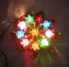 a multicolored christmas ornament is shown on a white surface with the light shining through it