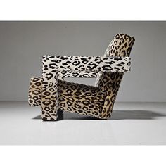 an animal print chair sitting on top of a white floor next to a gray wall