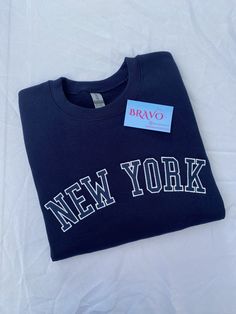 New York embroidered sweatshirt- Navy sweatshirt pictured Material: -50% Cotton, 50% Polyester -All crewneck sweatshirts are fleece Care instructions: -Machine wash cold, inside out, with like colors -Tumble dry low. -Medium iron. Do not iron embroidery.  Return & exchange policy: -All sales are final. No returns or exchanges due to sweatshirts being made to order, but please contact me for any questions or concerns. Varsity Crew Sweatshirt With Embroidered Text, Streetwear Fleece Sweatshirt With Embroidered Text, Fleece Sweatshirt With Embroidered Text For Streetwear, Trendy College Sweatshirt With Embroidered Logo, Trendy College Sweatshirt With Embroidered Text, Sporty Sweatshirt With Embroidered Text For Fall, Sporty Fall Sweatshirt With Embroidered Text, Everyday Crew Sweatshirt With Letter Embroidery, College Fleece Sweatshirt With Embroidered Text