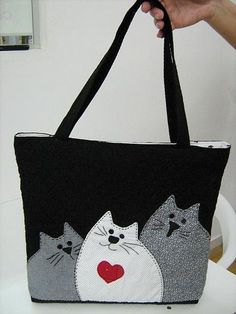 a hand holding a black bag with cats on it