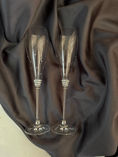 two wine glasses sitting next to each other on a black satin covered tablecloth,