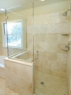 a bathroom with a walk in shower next to a bathtub and sink under a window