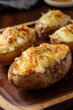 baked potatoes with cheese and chives on a wooden cutting board