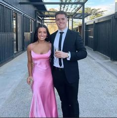 a man and woman standing next to each other in front of a building wearing formal wear