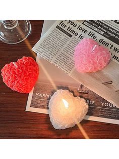 two heart shaped candles sitting on top of a newspaper