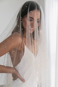 a woman wearing a wedding veil with pearls on it