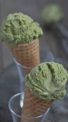 two scoops of green ice cream sitting in small cups on top of a table