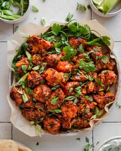 a bowl filled with chicken and greens on top of a white tile floor next to other dishes