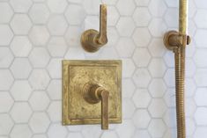 a gold faucet mounted to the side of a wall next to a shower head