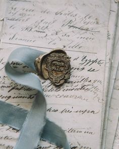 a waxed seal sitting on top of an old letter with blue ribbon around it