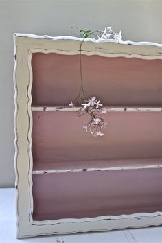 an old book shelf with flowers hanging from it