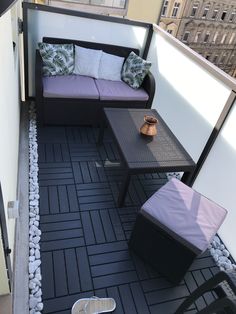 a small balcony with two couches and a coffee table on the floor next to it