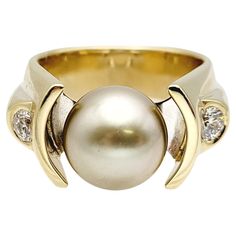 Ring size: 10 Introducing a stunning Cultured Tahitian Pearl & Diamond cocktail ring, a true embodiment of elegance and sophistication. Crafted in 14-karat yellow & white gold, this exquisite piece weighs 22.79 grams, ensuring a substantial and luxurious feel on your finger. The centerpiece of this remarkable ring is a lustrous Tahitian Pearl with a diameter of 11.36 mm. Its deep, dark hue exudes an air of mystery and allure, capturing the essence of the exotic Tahitian waters. On either side of High Luster Round Cut Rings For Formal Occasions, Formal High Luster Round Cut Rings, Formal Round Cut High Luster Rings, Elegant Formal Rings With High Luster, Timeless High Luster Rings For Formal Occasions, Luxury Tahitian Pearl Jewelry For Anniversary, Elegant High Luster Rings For Formal Occasions, Luxury Tahitian Pearl Anniversary Jewelry, Luxury Yellow Gold Pearl Ring With Center Stone