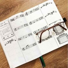 an open notebook with music notes and glasses on the page, next to a pair of eyeglasses