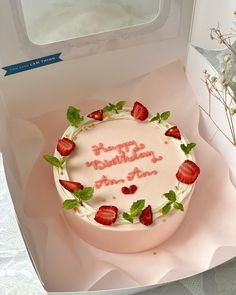 a birthday cake with strawberries on top in a box