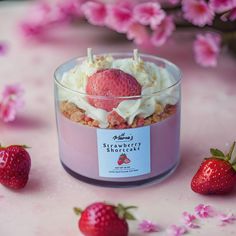 strawberry shortcake with whipped cream and strawberries on pink tablecloth next to flowers