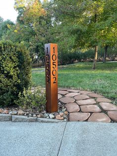 a sign that is on the side of a road in front of some grass and trees