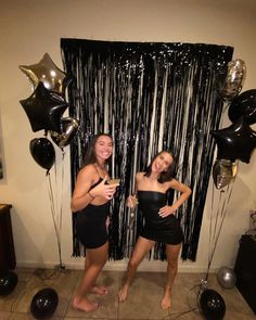 two women standing next to each other in front of balloons