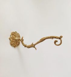 an ornate gold hook on a white wall