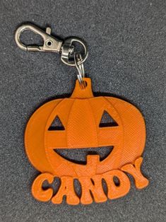 an orange pumpkin shaped key chain with the words candy on it