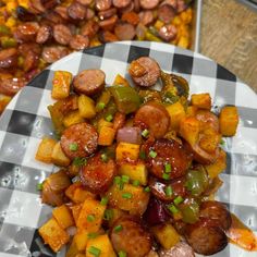 a white plate topped with sausages and potatoes on top of a checkered table cloth